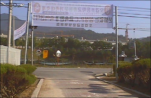 정문에서 본 현수막. 도로 건너편 삼연PCE 공장의 대형 크레인이 보인다. 